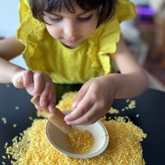 Babymädchen spielt gerne mit dem gefärbten Reis